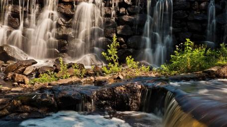 Majestic Waterfall Over Rocks and Greenery wallpaper