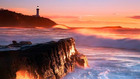Lighthouse at Sunset Over Waves wallpaper