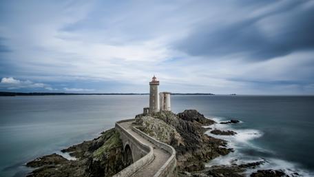 Lighthouse on a Rocky Island by the Sea wallpaper
