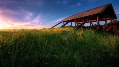 Serene Meadow at Dusk Featuring a Rustic Roof Structure wallpaper
