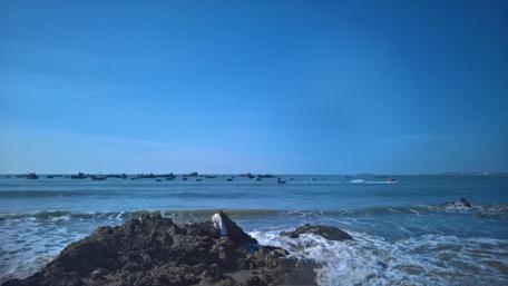 Serene Beach with Fishing Boats and Gentle Waves wallpaper