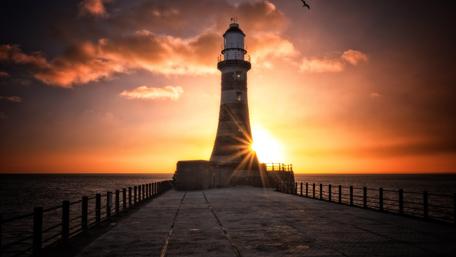 Lighthouse at Sunset Over the Sea wallpaper