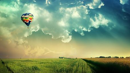 Colorful Hot Air Balloon Soaring Above Fields wallpaper