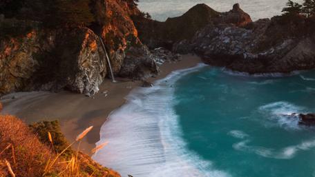 Serene Coastal Escape with Waterfall and Waves wallpaper