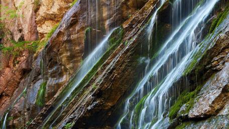 Majestic Waterfall Cascading Down Rocky Cliffs wallpaper