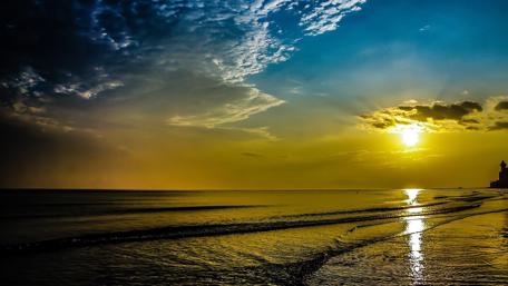 Golden Sunrise Over Tranquil Beach Waters wallpaper