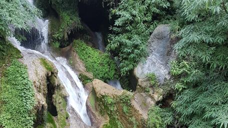 Serene Waterfall Cascading Over Lush Rocks wallpaper