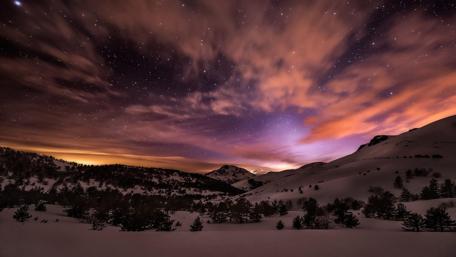 Majestic Starry Night Over Snowy Mountains wallpaper