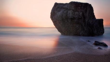 Serene Beach at Dawn with Majestic Rock Formation wallpaper