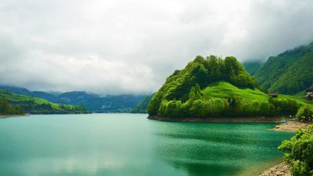 Serene Swiss Lake Amidst Lush Hillside Surroundings wallpaper