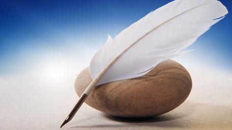 Elegant Feather Pen on a Serene Stone Surface wallpaper