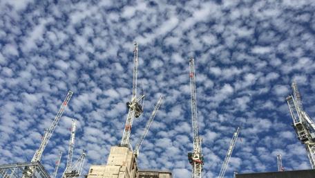 Dynamic Skyline with Tower Cranes and Dramatic Clouds wallpaper