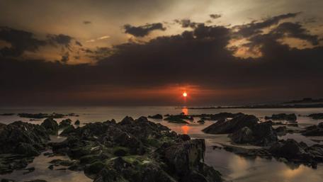 Serene Dark Sunset Over Rocky Coastline wallpaper