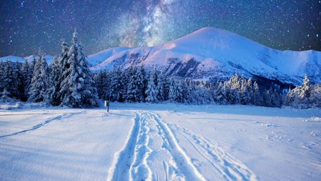 Milky way on the night sky over the snowy mountains wallpaper
