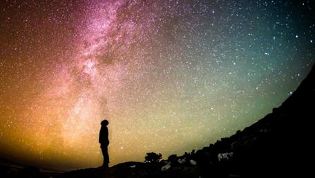 Man looking up the starry night sky wallpaper