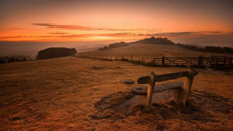 Lonely bench in the field at the sunrise wallpaper