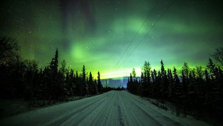 Northern lights over the snowy road wallpaper