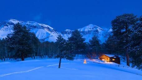 Winter Wonderland Christmas Scene with Cabin and Snowy Peaks wallpaper