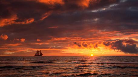 Tranquil Sunset Over Ocean with Sailing Ship wallpaper