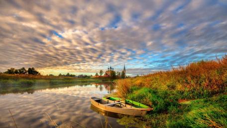Serene Autumn Landscape with Boat and Reflection in Waterway wallpaper