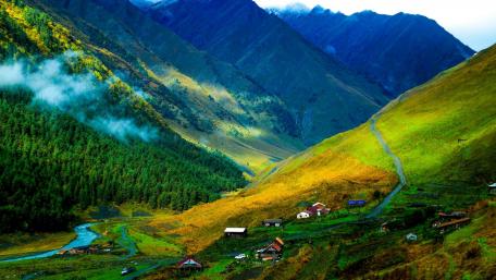 Breathtaking Highland Village Landscape Amidst Majestic Mountains wallpaper