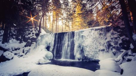 Serene Winter Waterfall Scene Amidst Snowy Forest wallpaper
