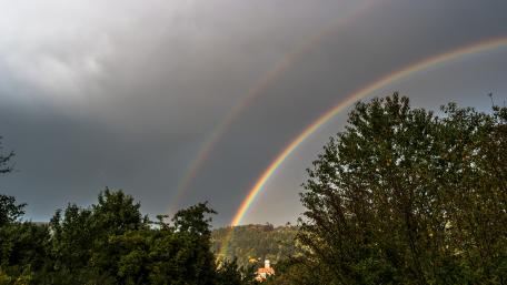 Vibrant Double Rainbow Above Lush Landscape wallpaper