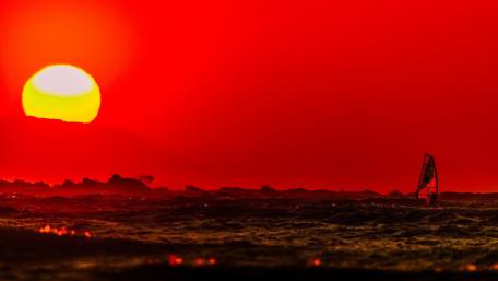 Vibrant Surfing at Sunset Over Red Sky Scene wallpaper