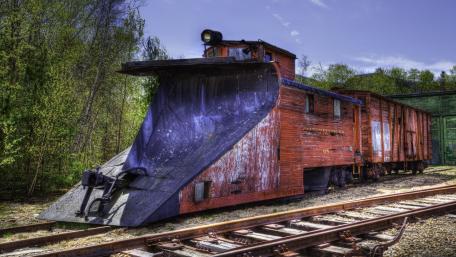 Rustic Railroad Snowplow on Tracks in Nature wallpaper