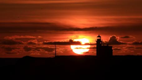 Silhouette of a Lighthouse Against a Vibrant Sunset wallpaper