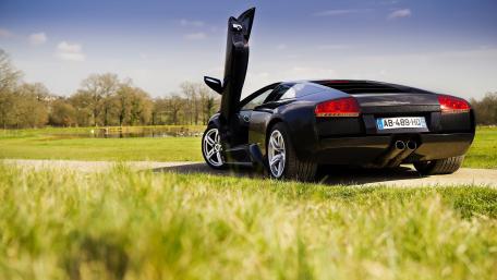 Sleek Black Lamborghini Under Clear Blue Sky wallpaper