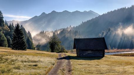 Serene Bavarian Cottage Amidst Misty Alps and Golden Autumn Grasslands wallpaper