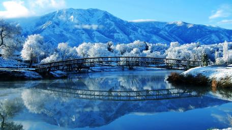 Winter Wonderland with Reflective Bridge Over Calm Water wallpaper