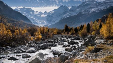 Rocky creek surrounded by snowy mountains wallpaper