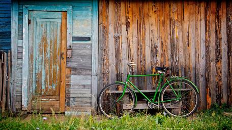A green bicycle in front of a cabin wallpaper