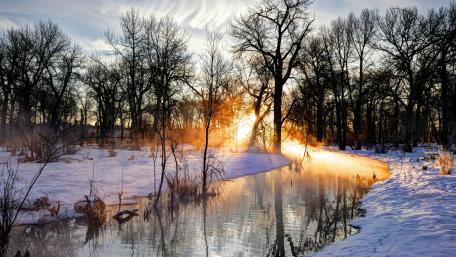 Serene Winter Sunset Over a Snowy Riverbank wallpaper