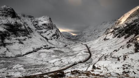 Winter Mountain Pass Surrounded by Snowy Peaks wallpaper
