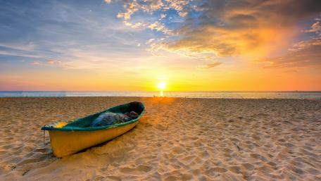 Serene Sunrise Over Sandy Beach with Boat wallpaper