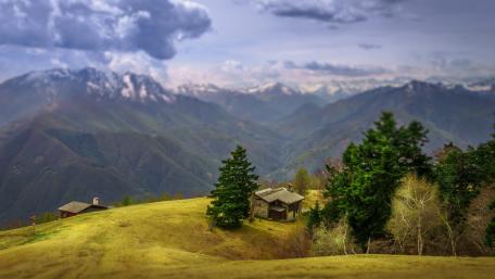 Serene Mountain Cottage Amidst Majestic Peaks wallpaper