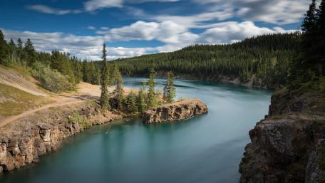 Tranquil River Surrounded by Lush Wilderness and Majestic Mountains wallpaper