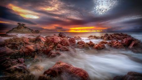 Breathtaking Sunset Over Rocky Shoreline wallpaper