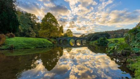 Serene Stone Bridge Reflected in Tranquil Waterway Morning Light wallpaper