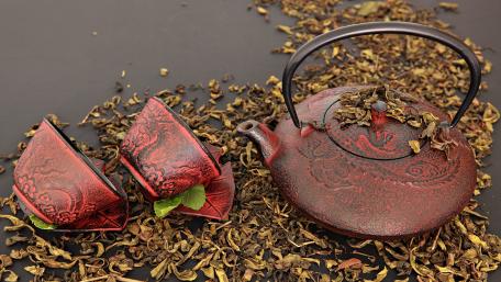 Elegant Teapot and Cups Surrounded by Tea Leaves wallpaper