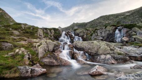 Majestic Waterfall Surrounded by Rocky Terrain wallpaper