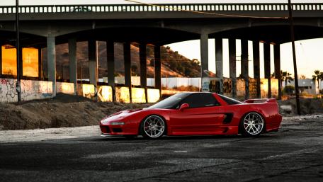 Sleek Red Sports Car Under a Sunset Bridge wallpaper