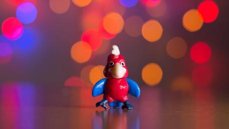 Cheerful Parrot Toy Amidst Colorful Bokeh Lights wallpaper