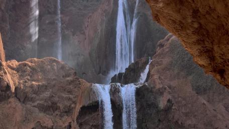 Majestic Waterfall Cascading Down Rocky Cliffs wallpaper