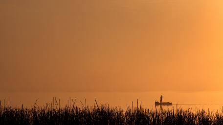 Boat silhouette on a lake at sunset wallpaper