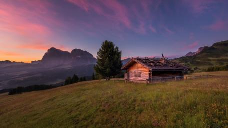 Log cabin in the mountain field wallpaper