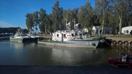 Serene Harbor Scene with Fishing Vessels and Lush Trees wallpaper
